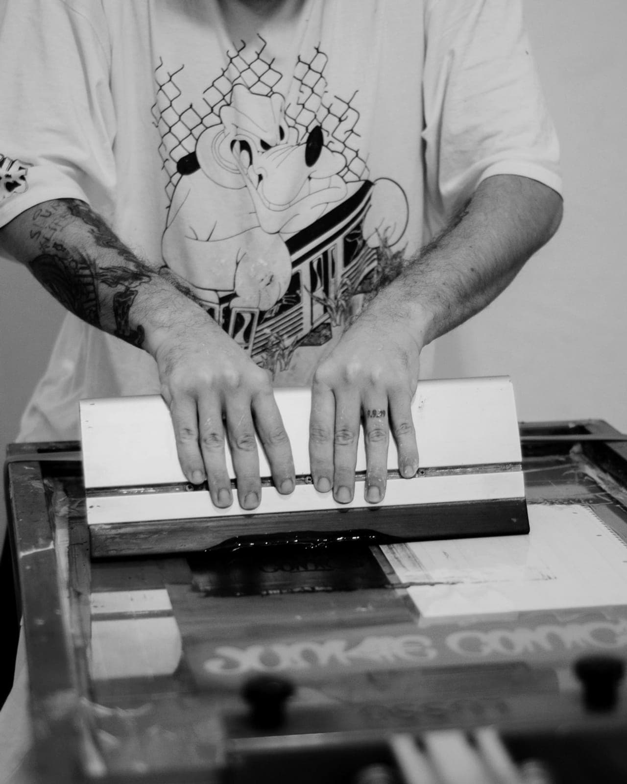 Hands pressing a design onto fabric at a screen printing bench